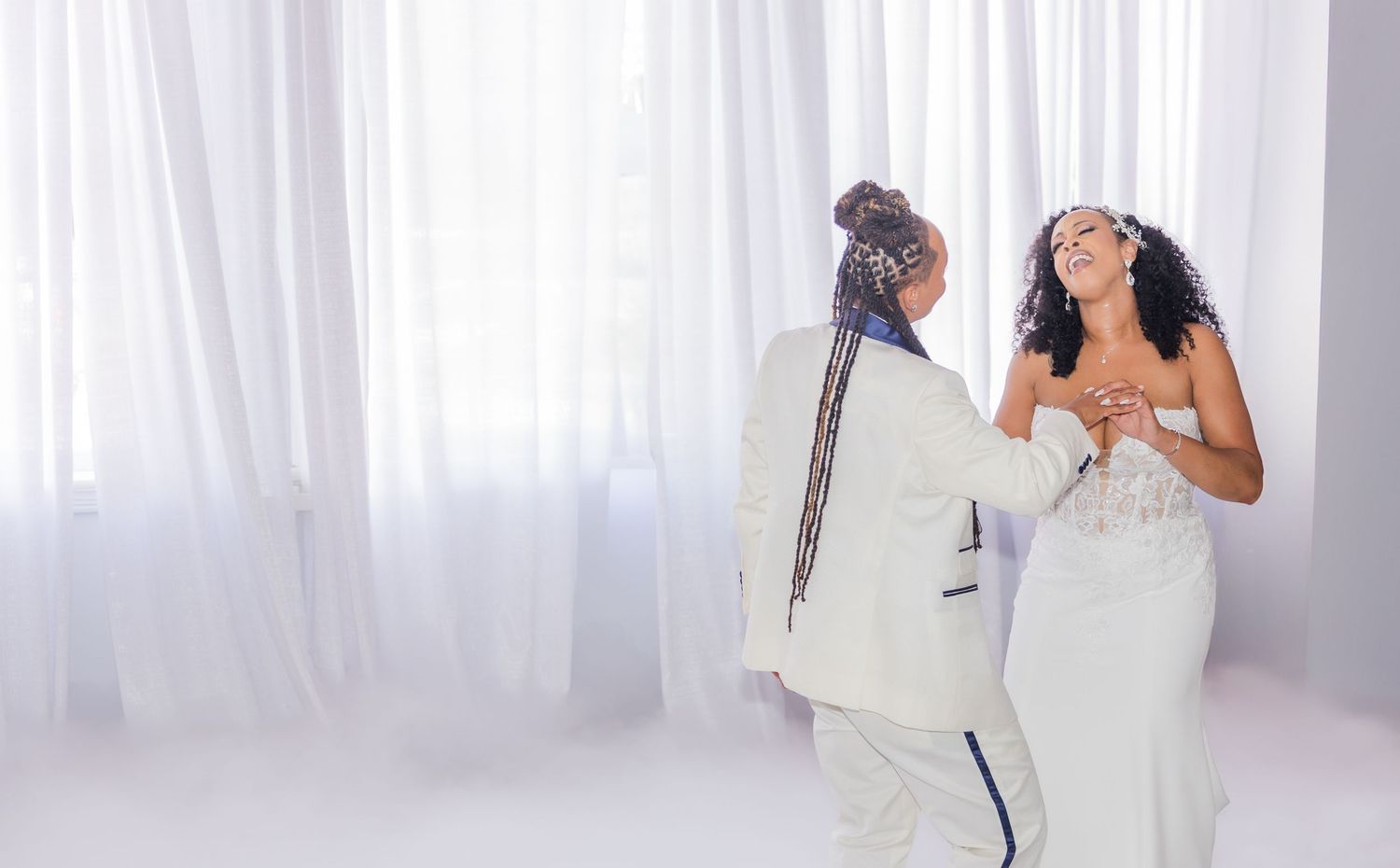 A romantic dance captured in an all-white venue with flowing curtains as backdrop.