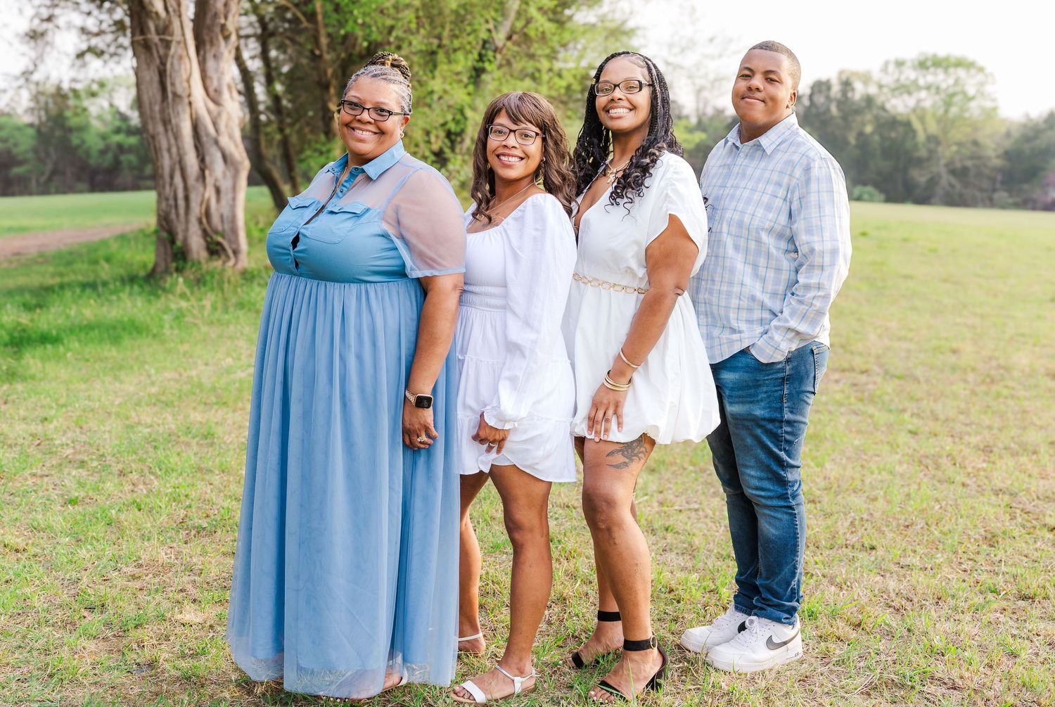 Four people pose together outdoors wearing coordinated white and blue outfits.