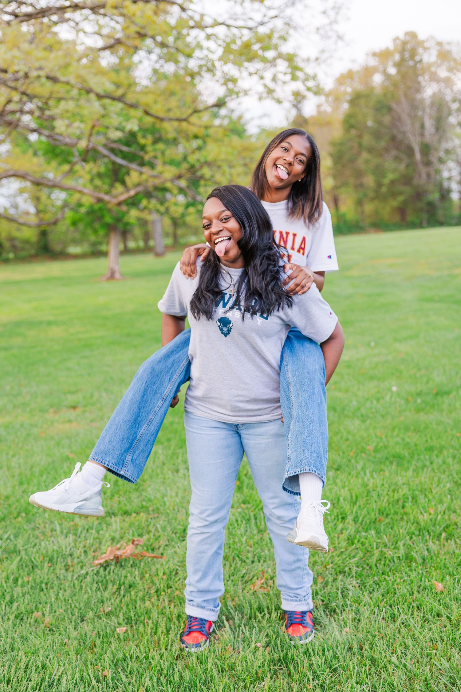 A person in casual denim and white t-shirt dances joyfully on green grass in a park.