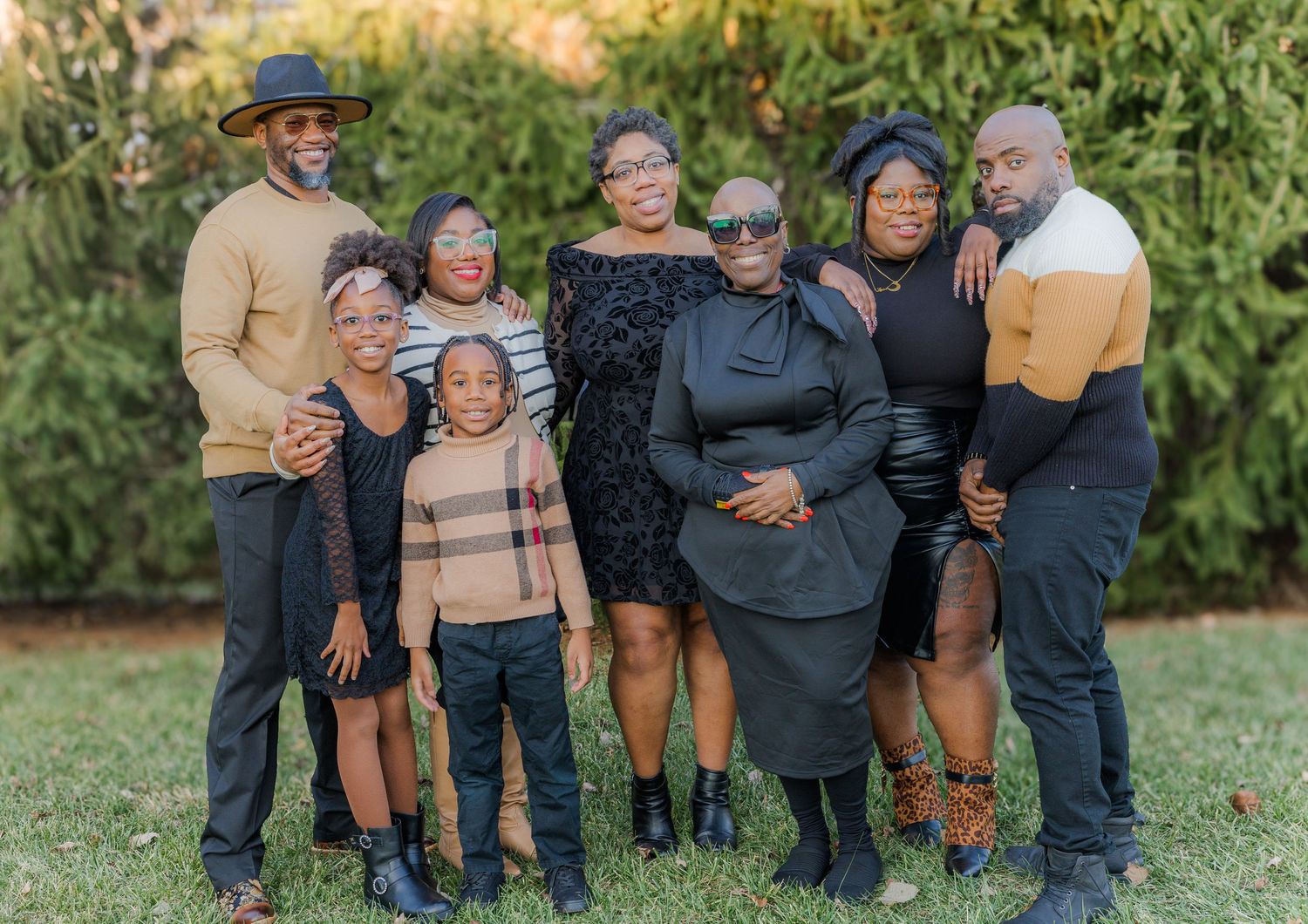 Family members gather in casual winter clothing for an outdoor portrait session in a natural setting.