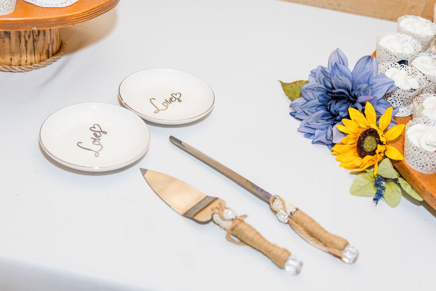 Wedding cake cutting set with decorative handles and blue floral accents on white tablecloth.