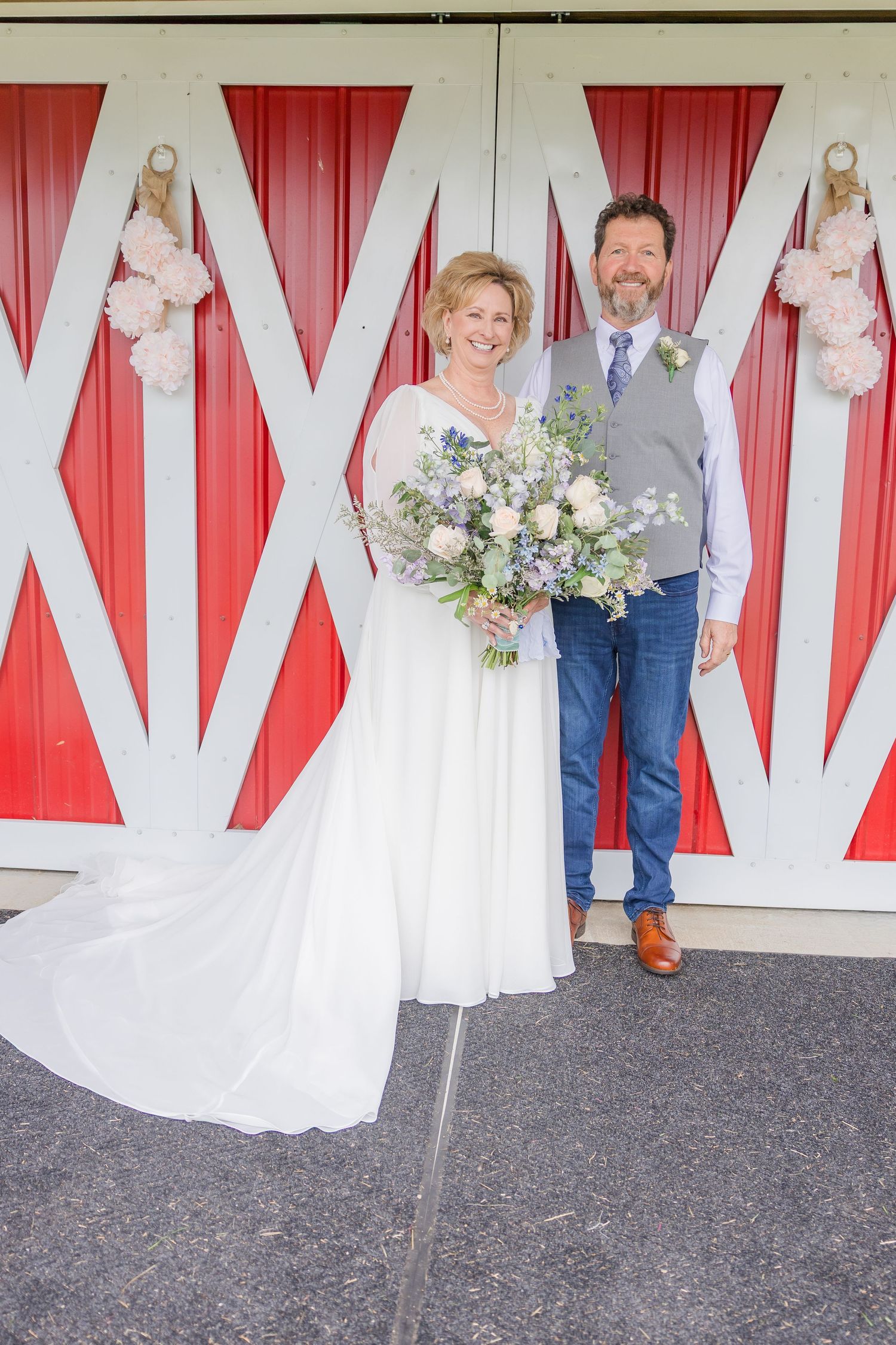 Wedding party poses against red and white draped backdrop at reception venue.