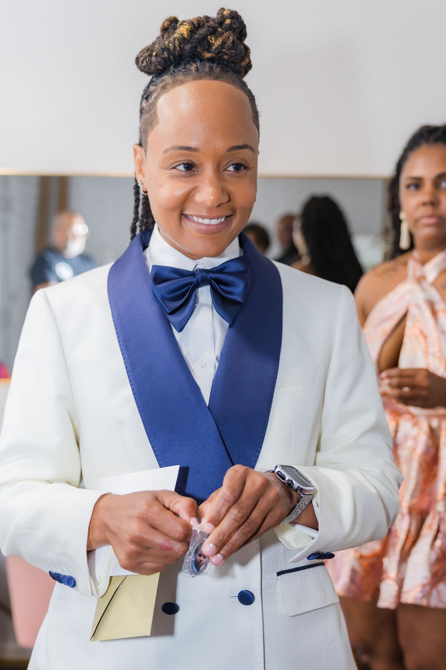 Someone in formal attire smiling while holding papers during a special occasion.