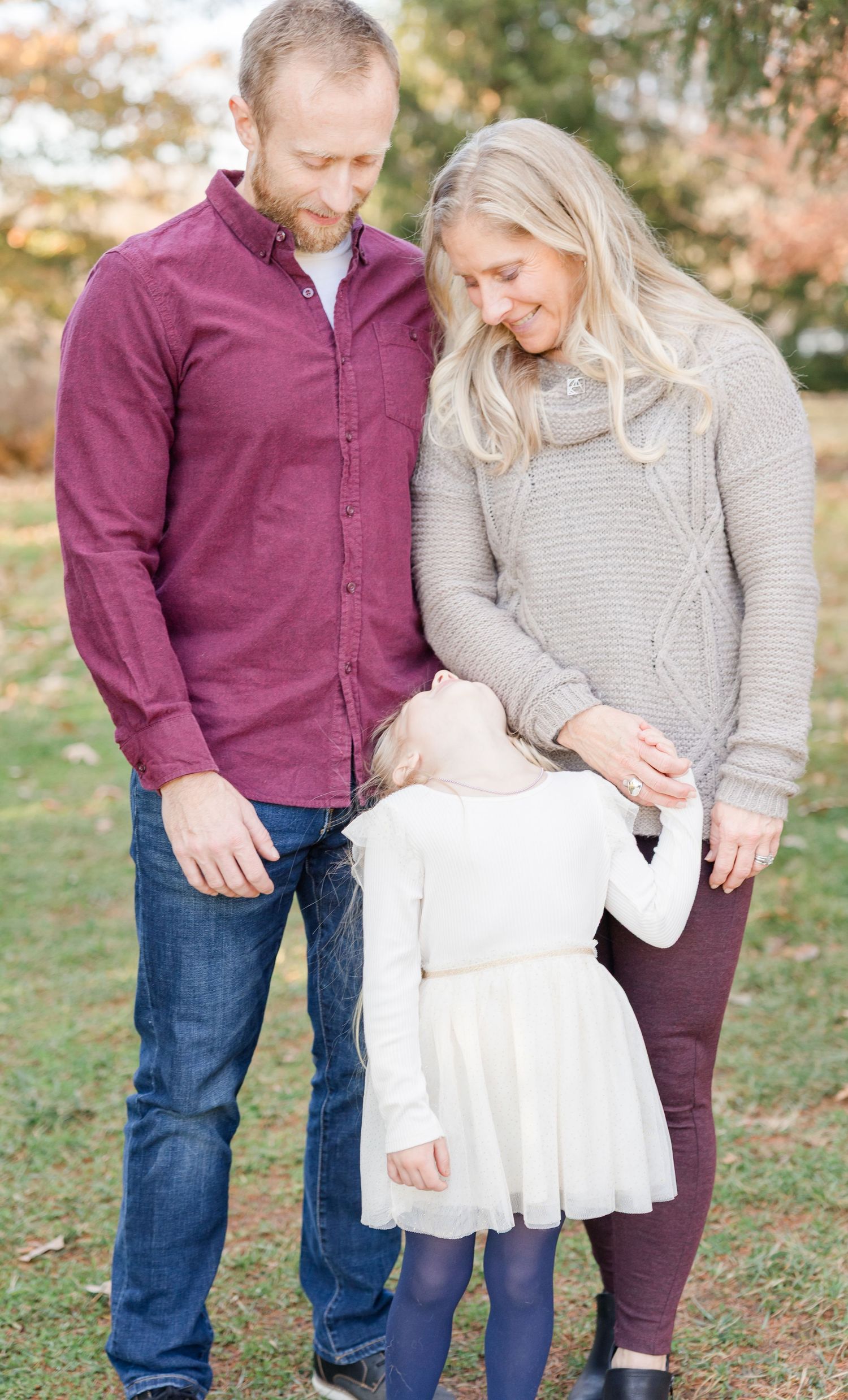 A couple in burgundy and gray casual wear share a tender moment outdoors during fall season.