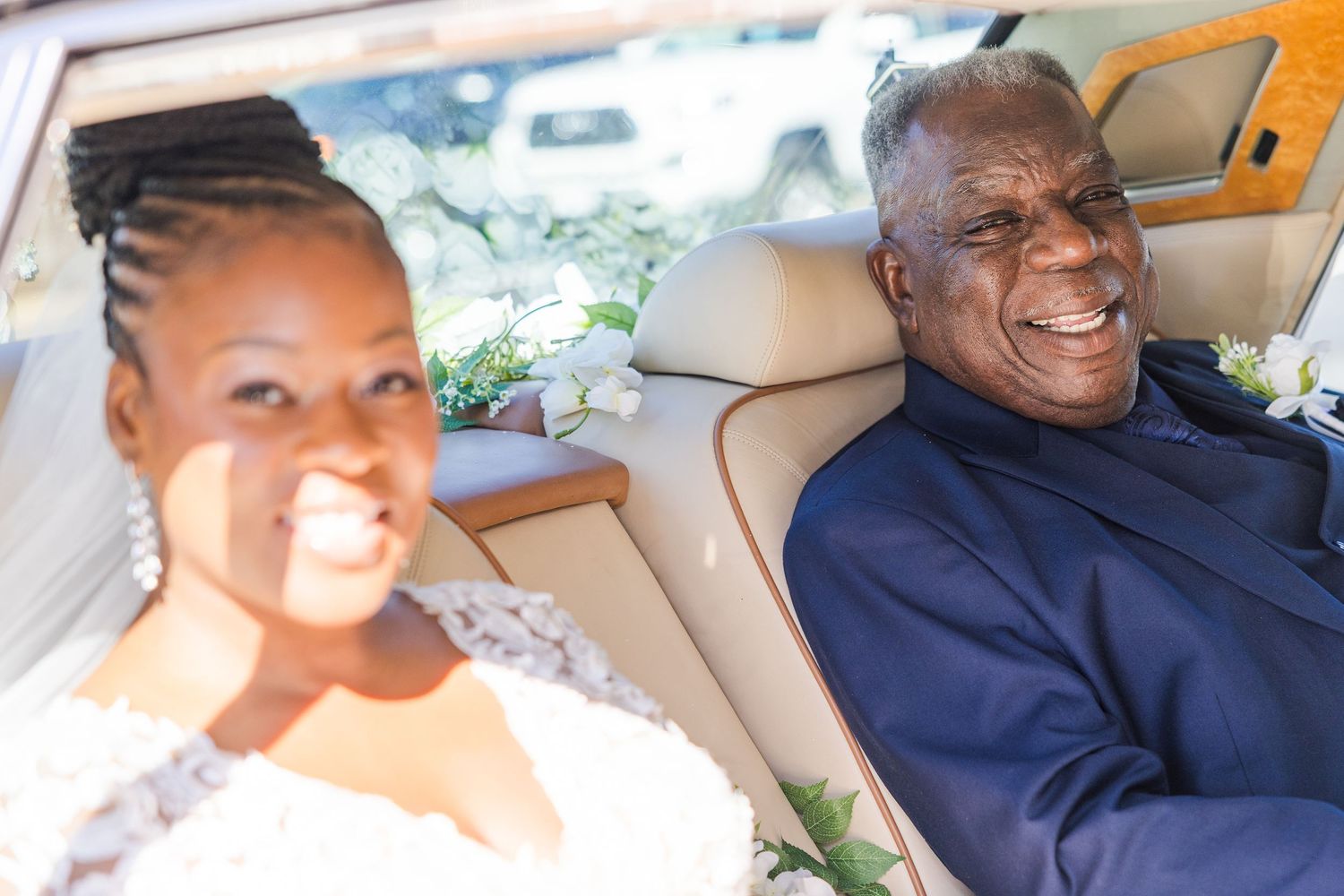 A group of people smile and laugh together while sitting in a car interior.