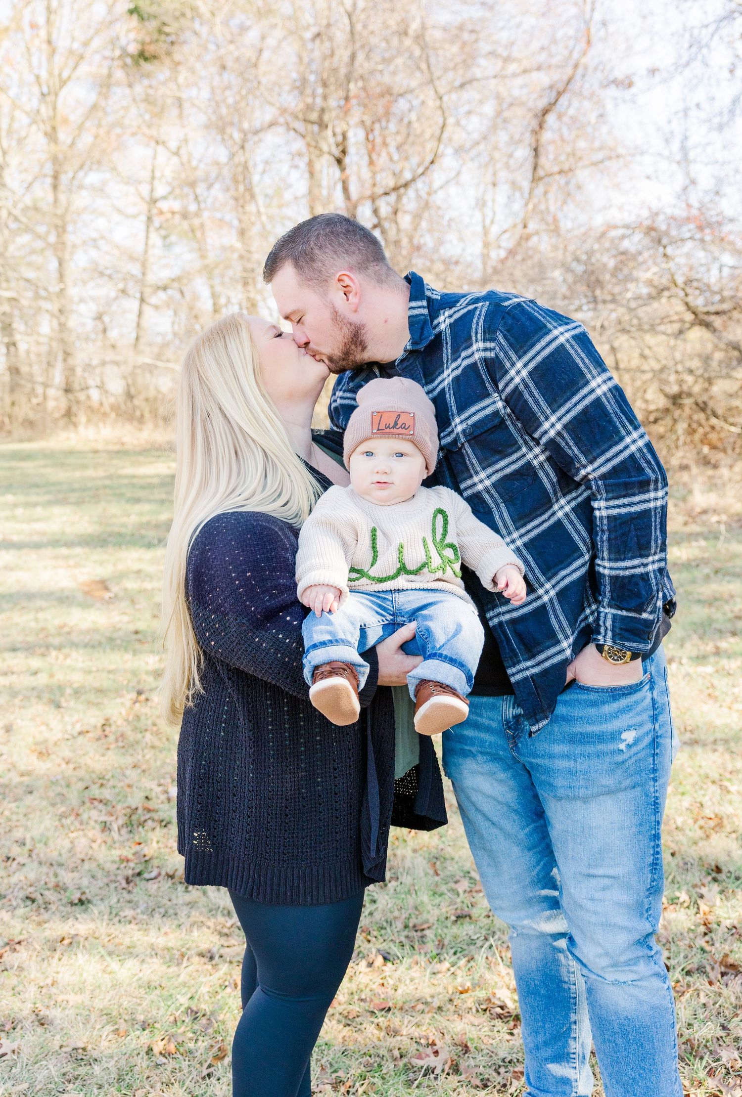 Parents playing with baby in casual outdoor setting.