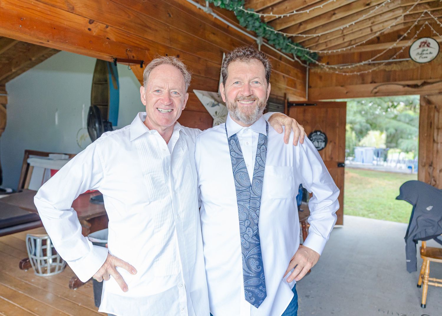 Wedding party members in formal attire posing together under a wooden pavilion.