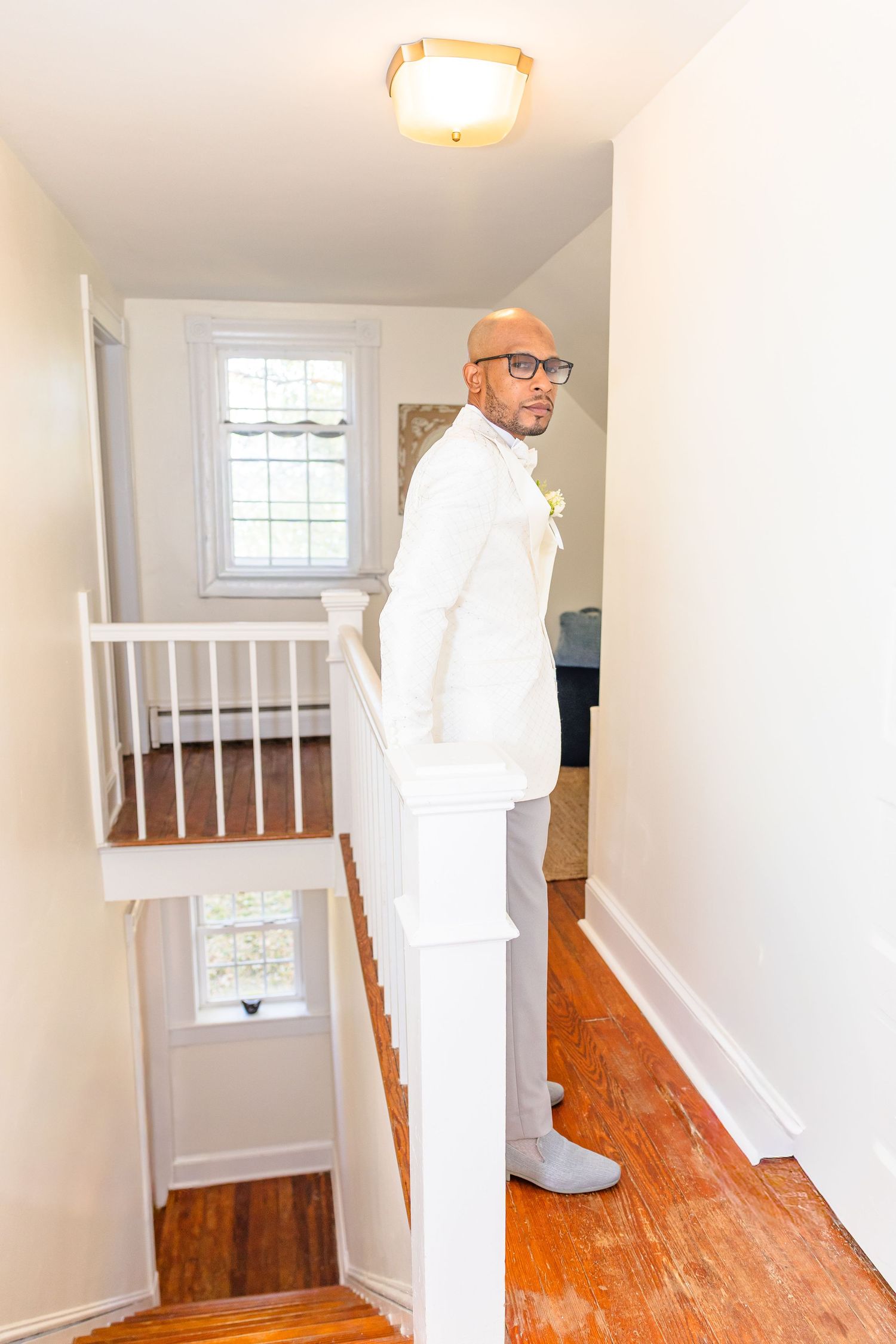 Bright hallway with hardwood floors, white walls, and natural light from windows showcases upstairs landing area.