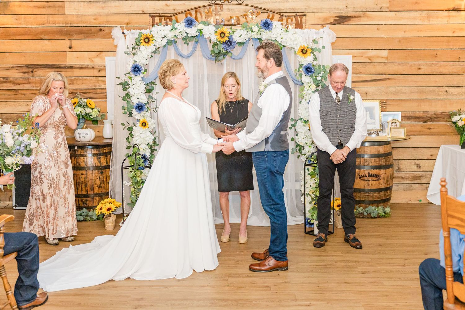 Wedding ceremony setup with wooden walls, sunflower decor, and guests in attendance.