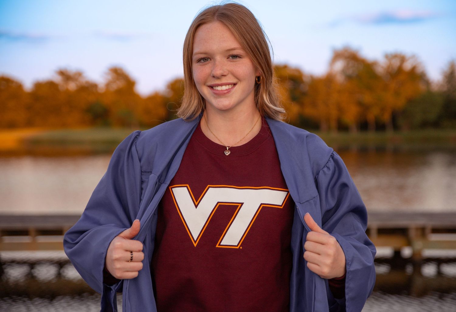 Virginia Tech student showing school spirit in maroon sweatshirt by lake.