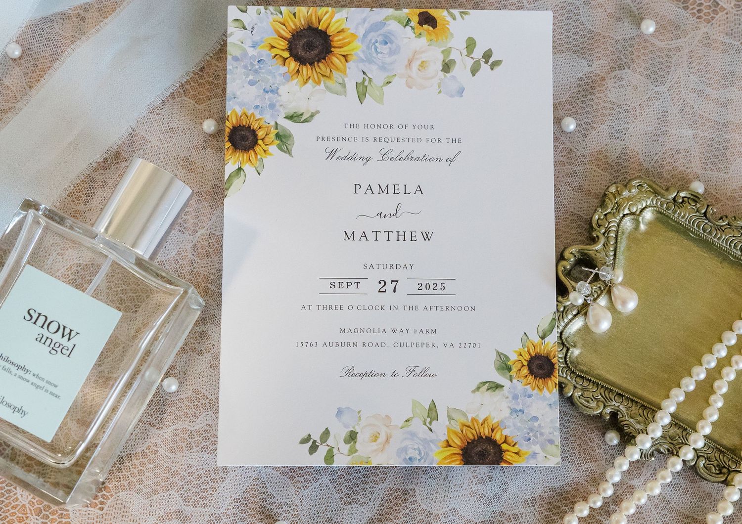 Wedding invitation with sunflower design and floral motifs displayed with perfume bottle.
