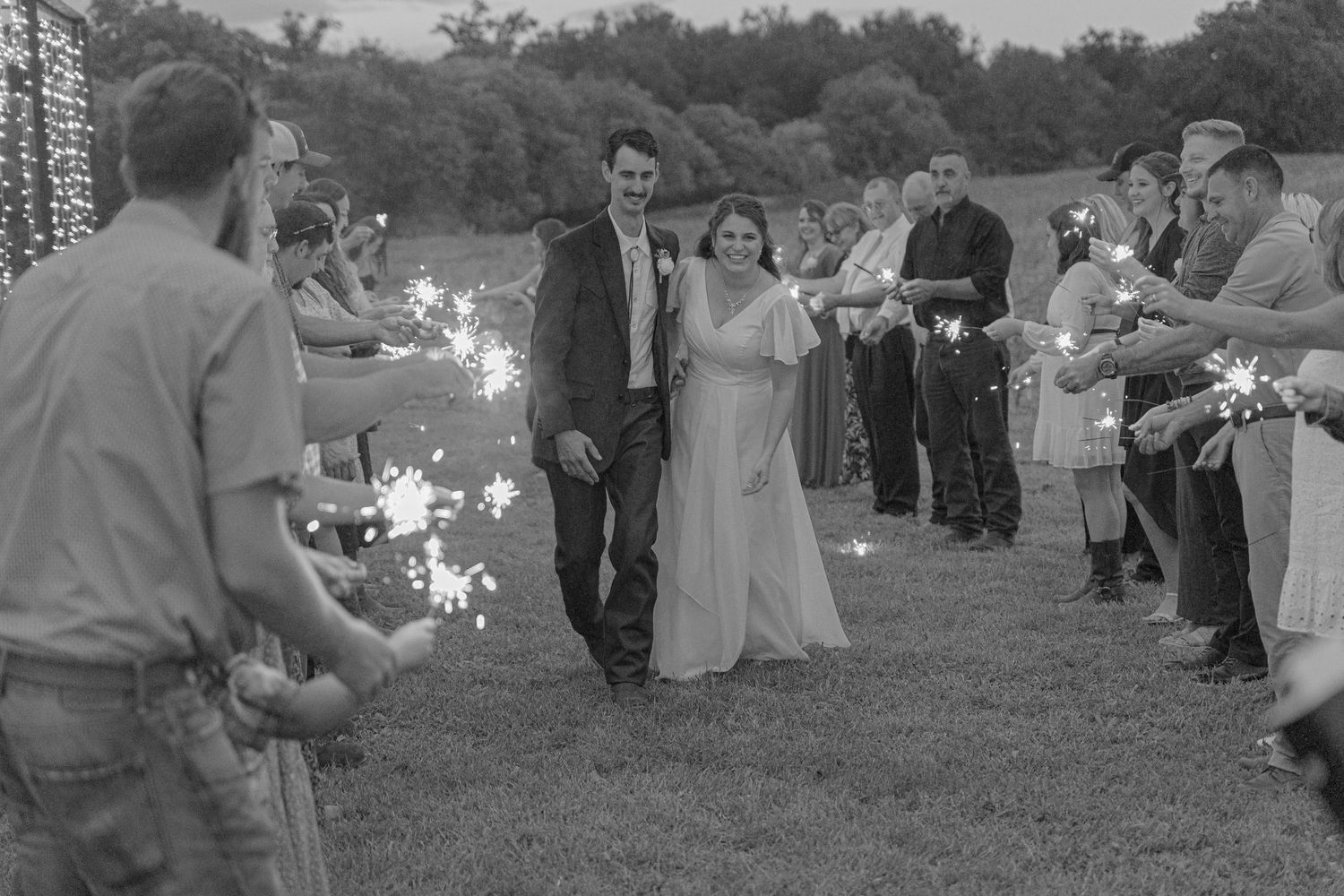 Wedding guests seated outdoors for ceremony in black and white photograph.