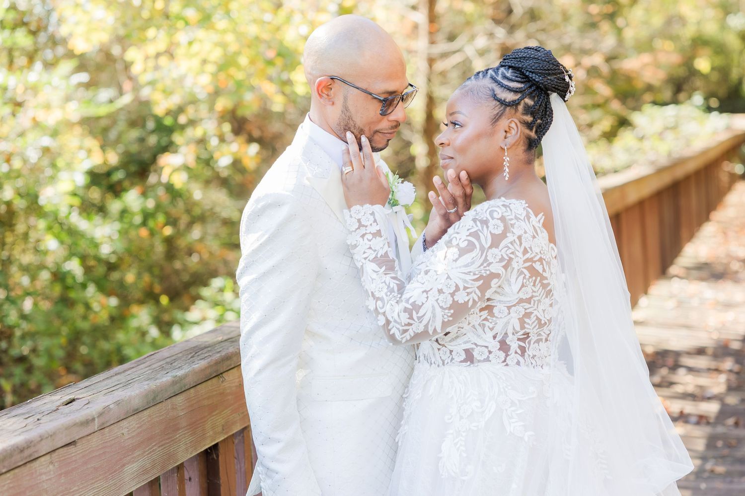 A couple shares an intimate moment in a garden setting wearing elegant white wedding attire.
