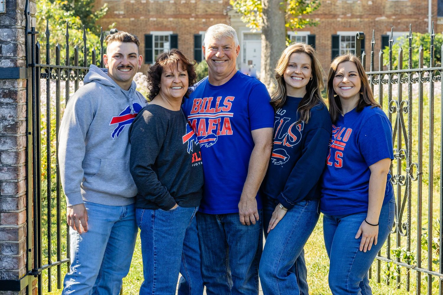 A group wearing Buffalo Bills fan gear poses together by an iron gate.