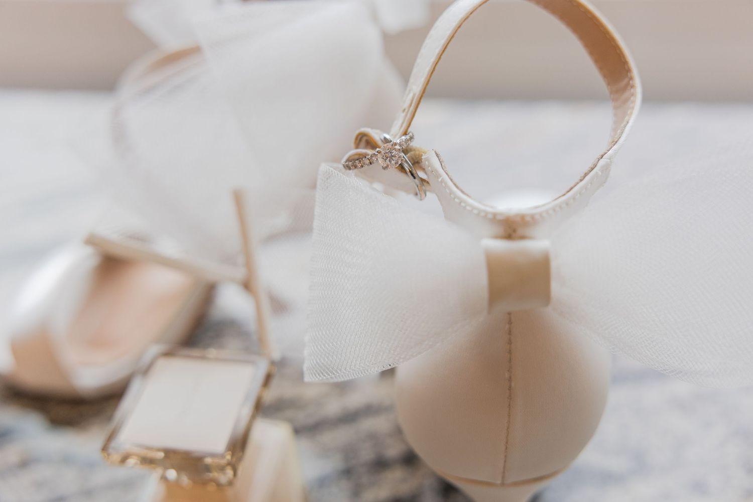 Wedding accessories including shoes and rings arranged on white surface.