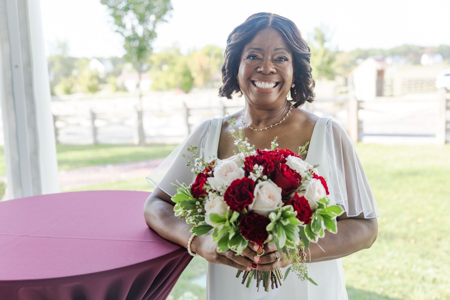 A wedding bouquet features deep red and white roses with delicate greenery.