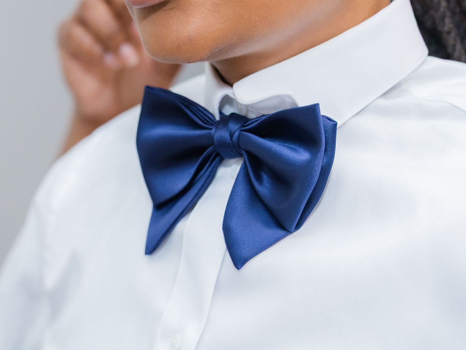 Close-up of navy blue bow tie with white formal shirt.