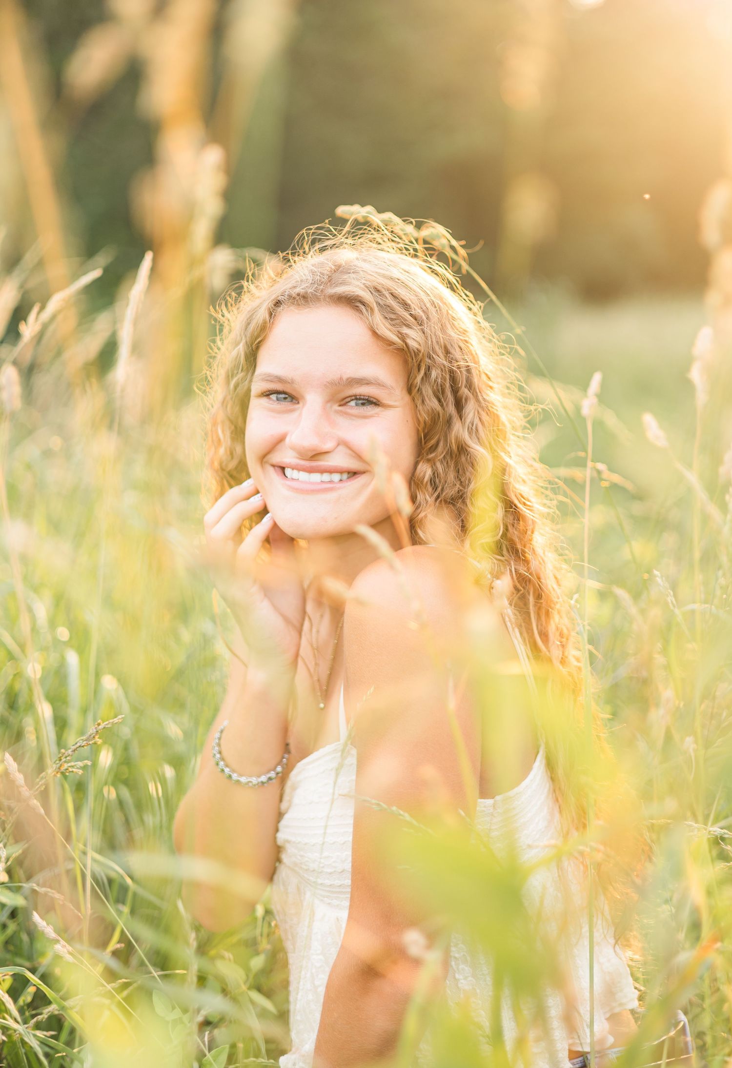 A dreamy golden hour portrait in a white top amidst tall summer grass.