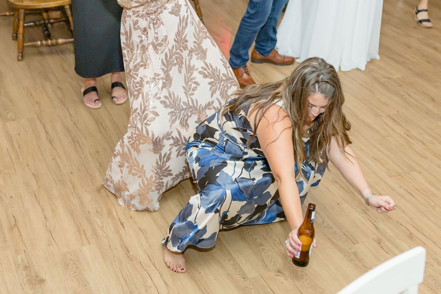 People search for items on a wooden dance floor during a wedding game.