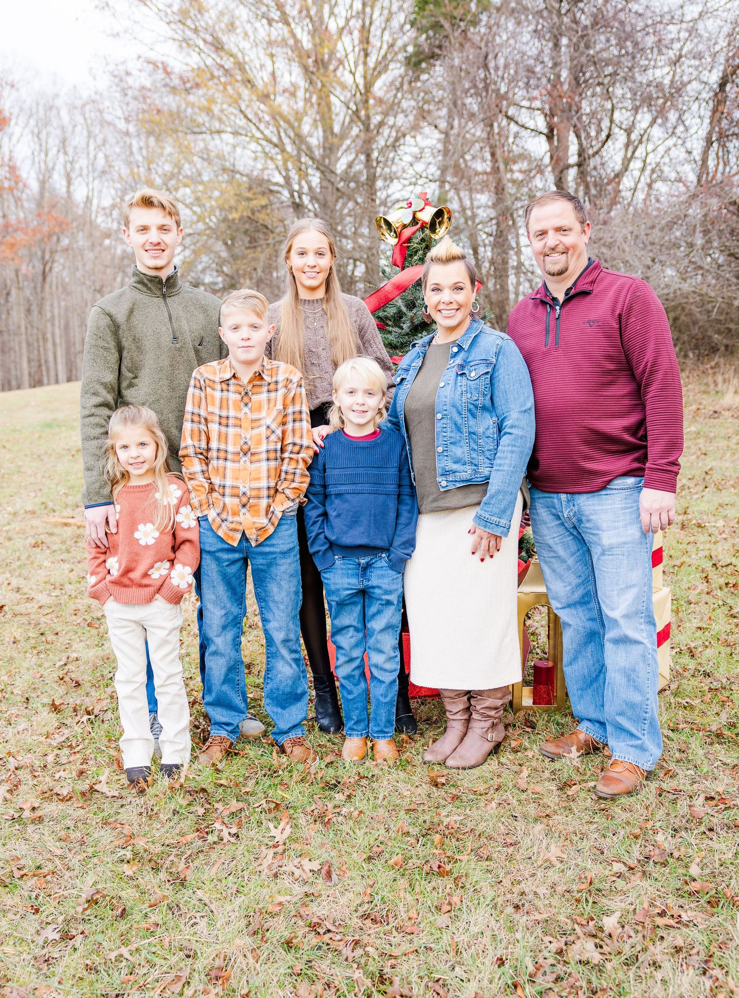 Family members pose together on hillside during autumn photo session.