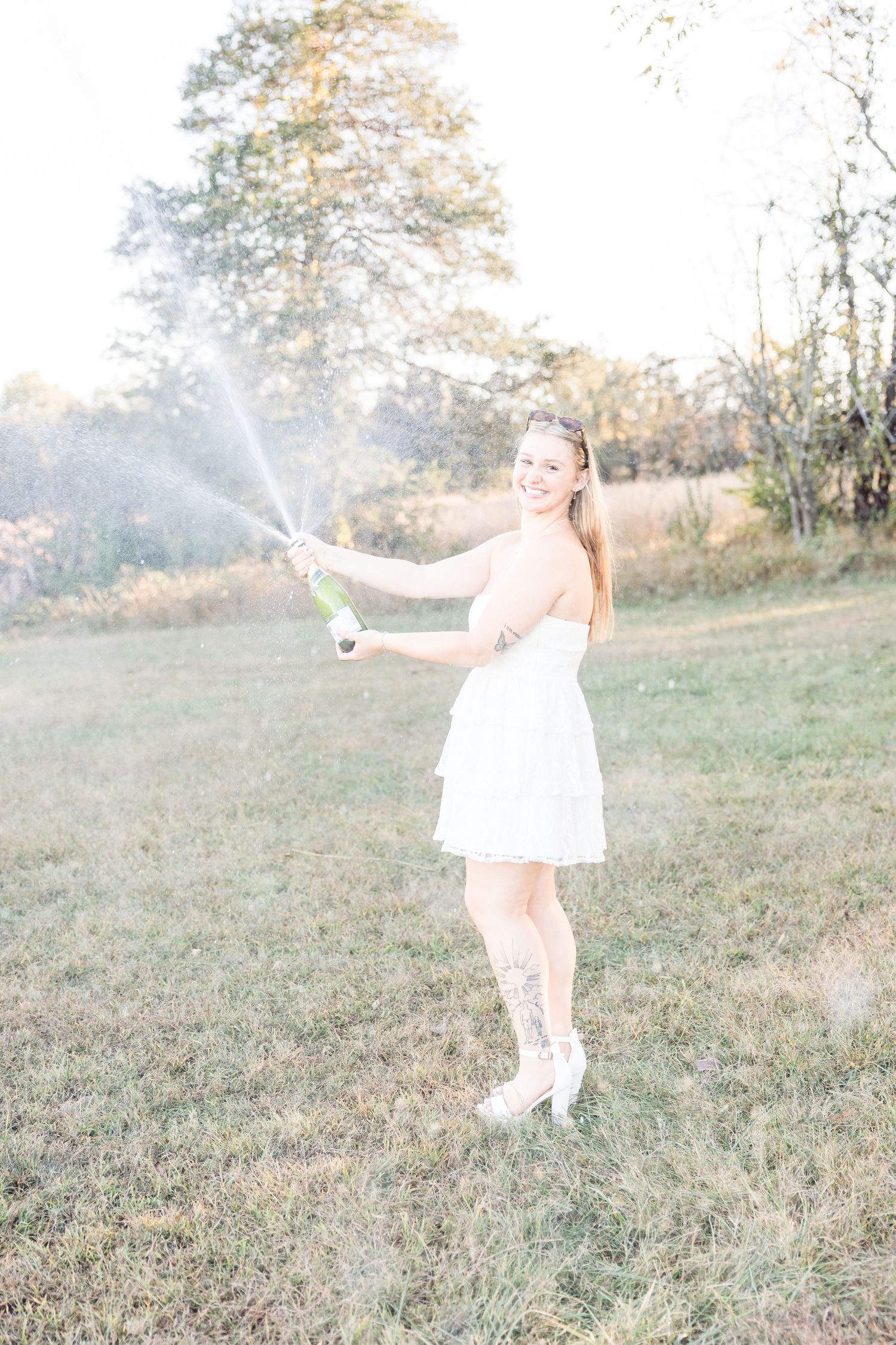 A person in white dress twirls and dances in a sunlit meadow.