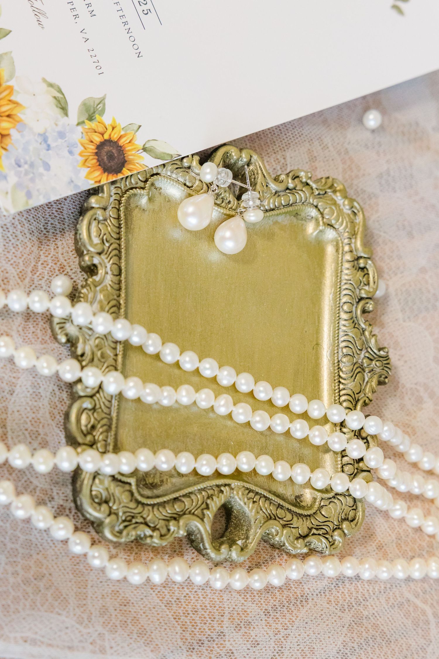 Vintage gold frame with pearl necklace and sunflower invitation detail.