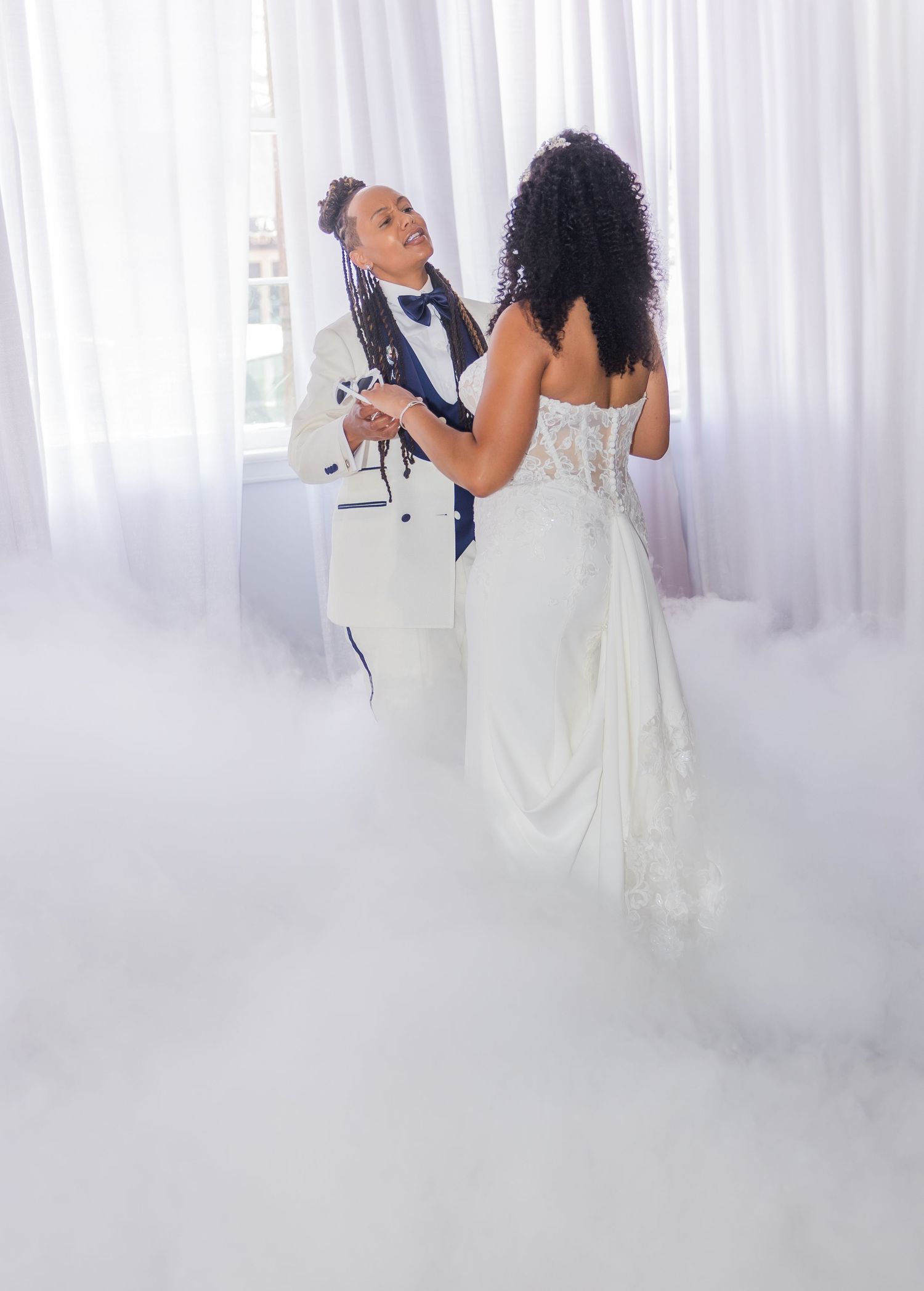 A romantic first dance moment surrounded by dreamy fog effects and white curtains.