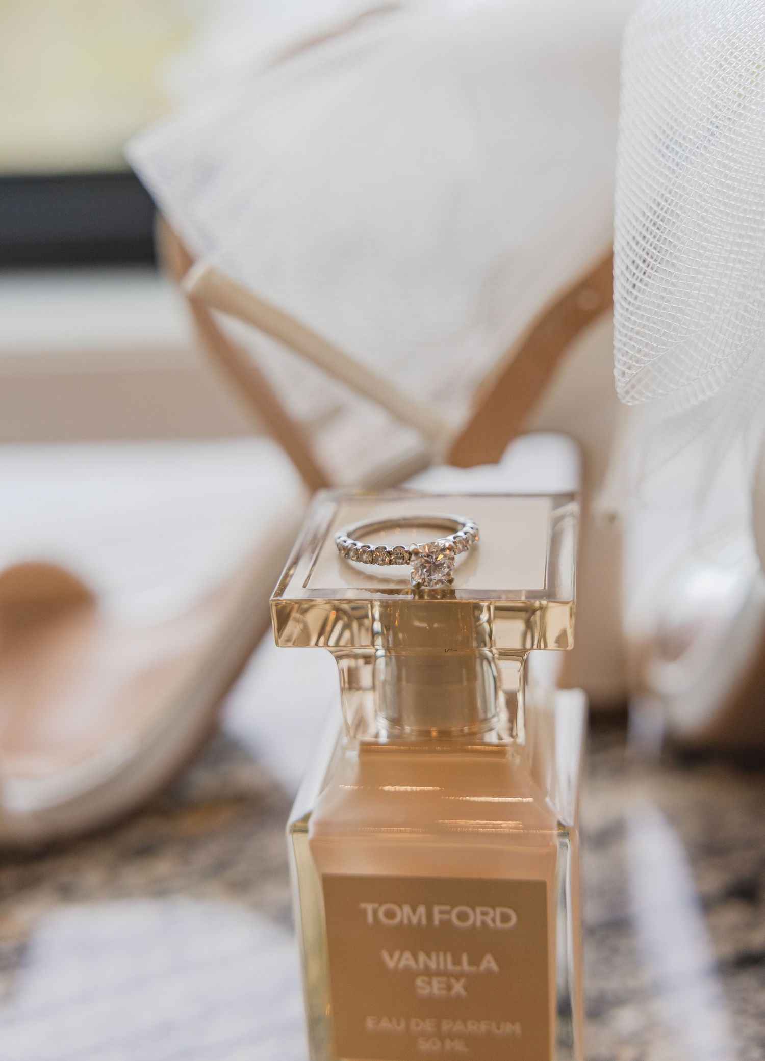 Tom Ford Vanilla Sex perfume bottle with wedding ring displayed on clear surface.