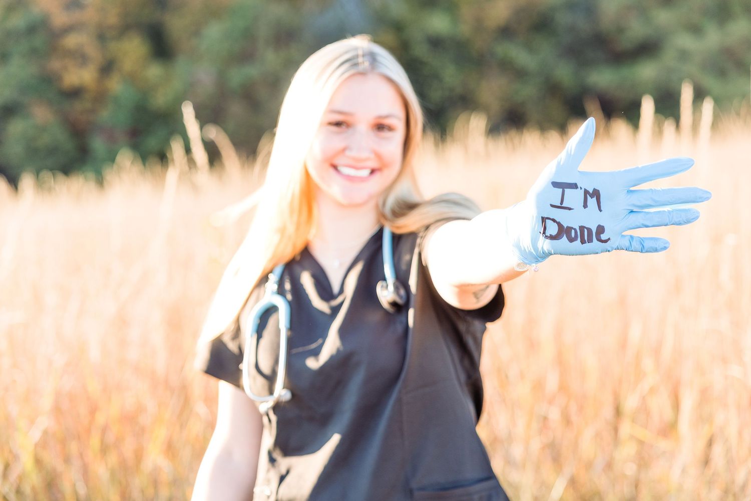 A celebratory outdoor portrait with handwritten signs in golden sunlight.