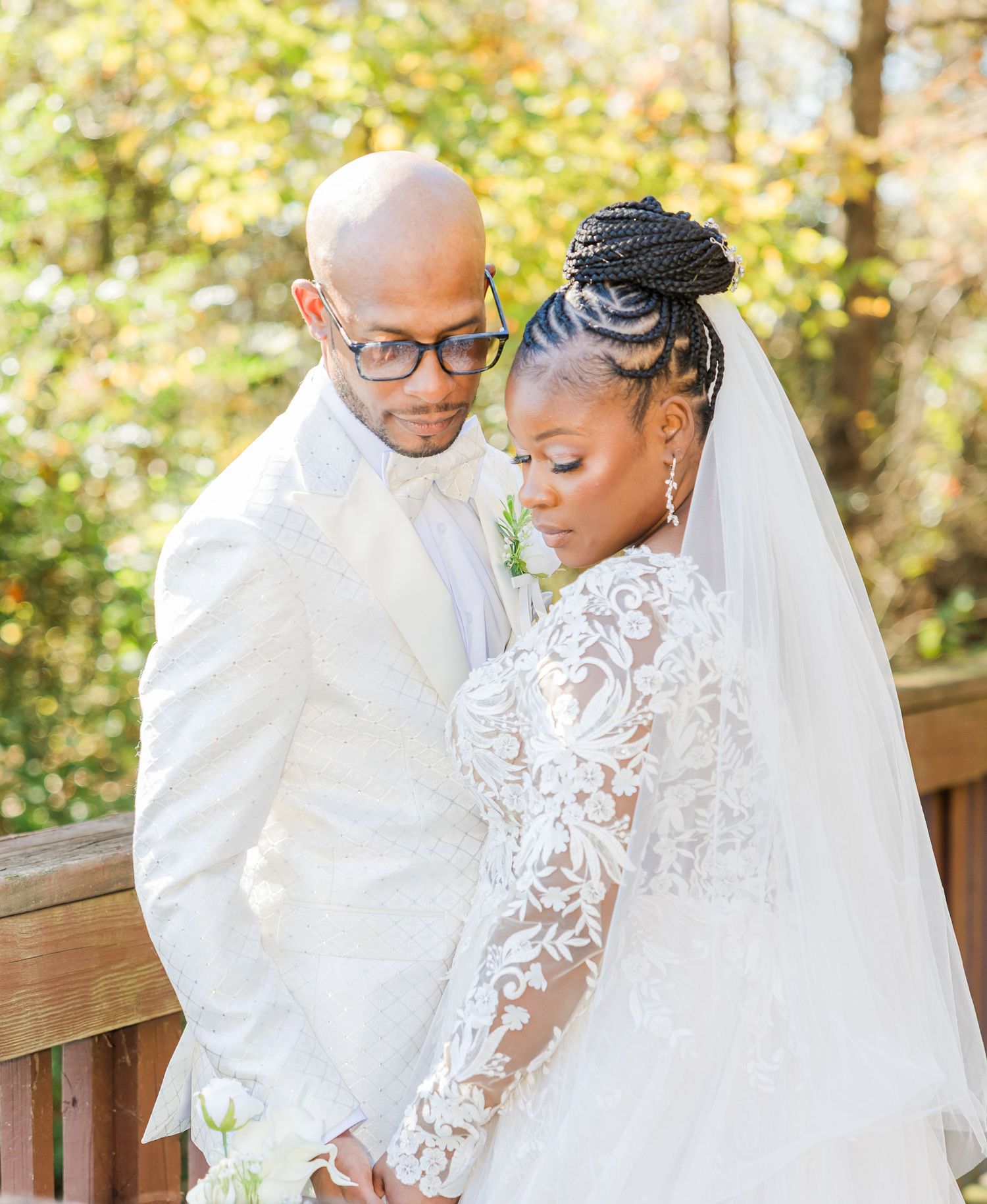 A couple shares an intimate moment during their outdoor autumn wedding ceremony in a natural wooded setting.