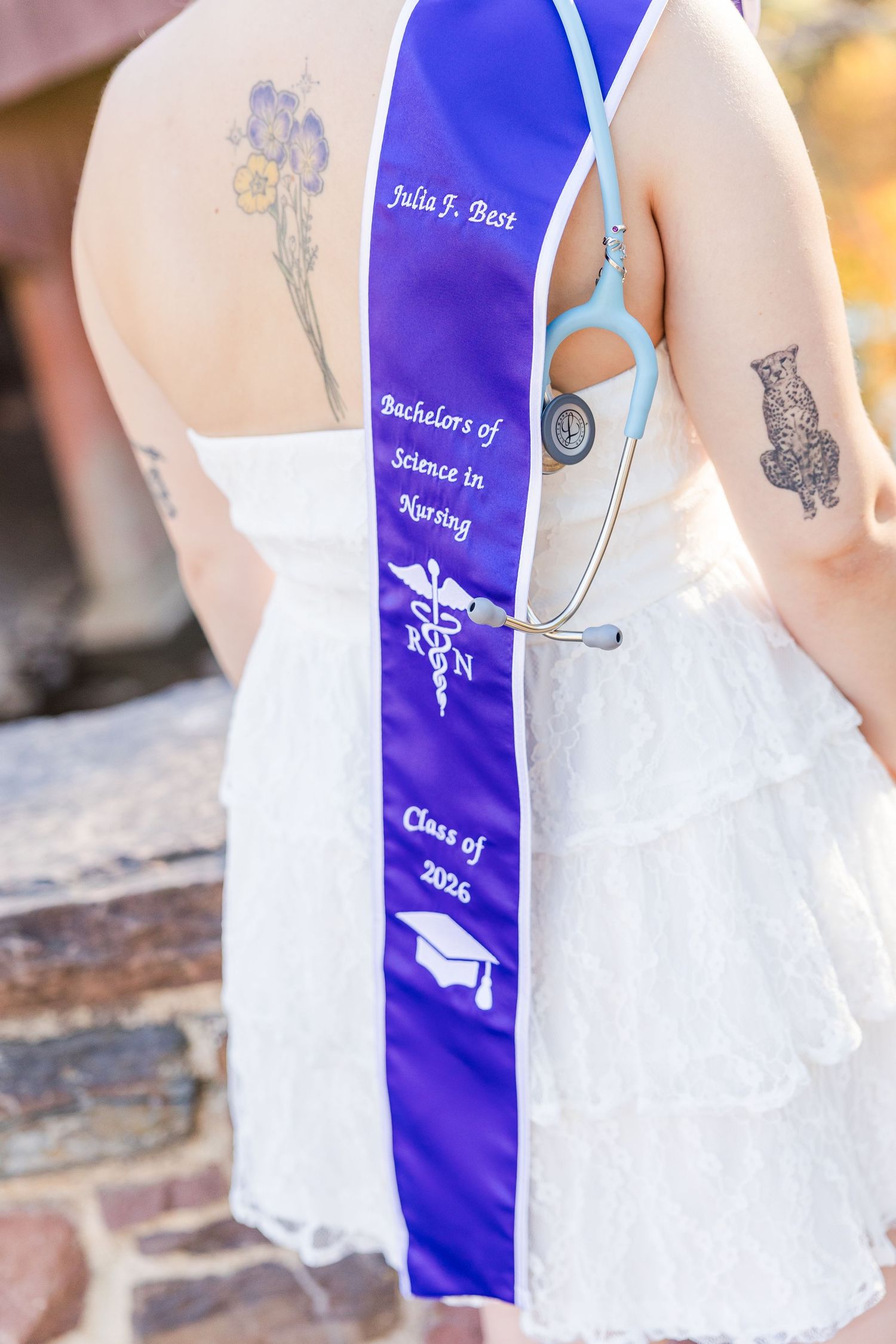 A white dress with royal blue graduation sash showing medical symbols and text.