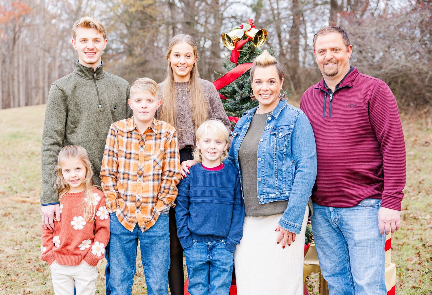 A series of outdoor family portraits taken in front of bare winter trees with festive holiday decor.