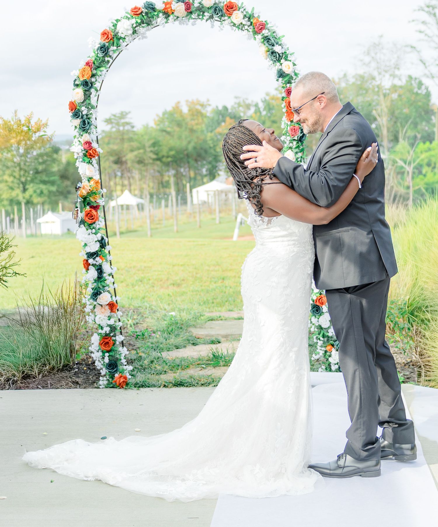 Wedding ceremony setup with floral arch and white chairs overlooking waterfront.