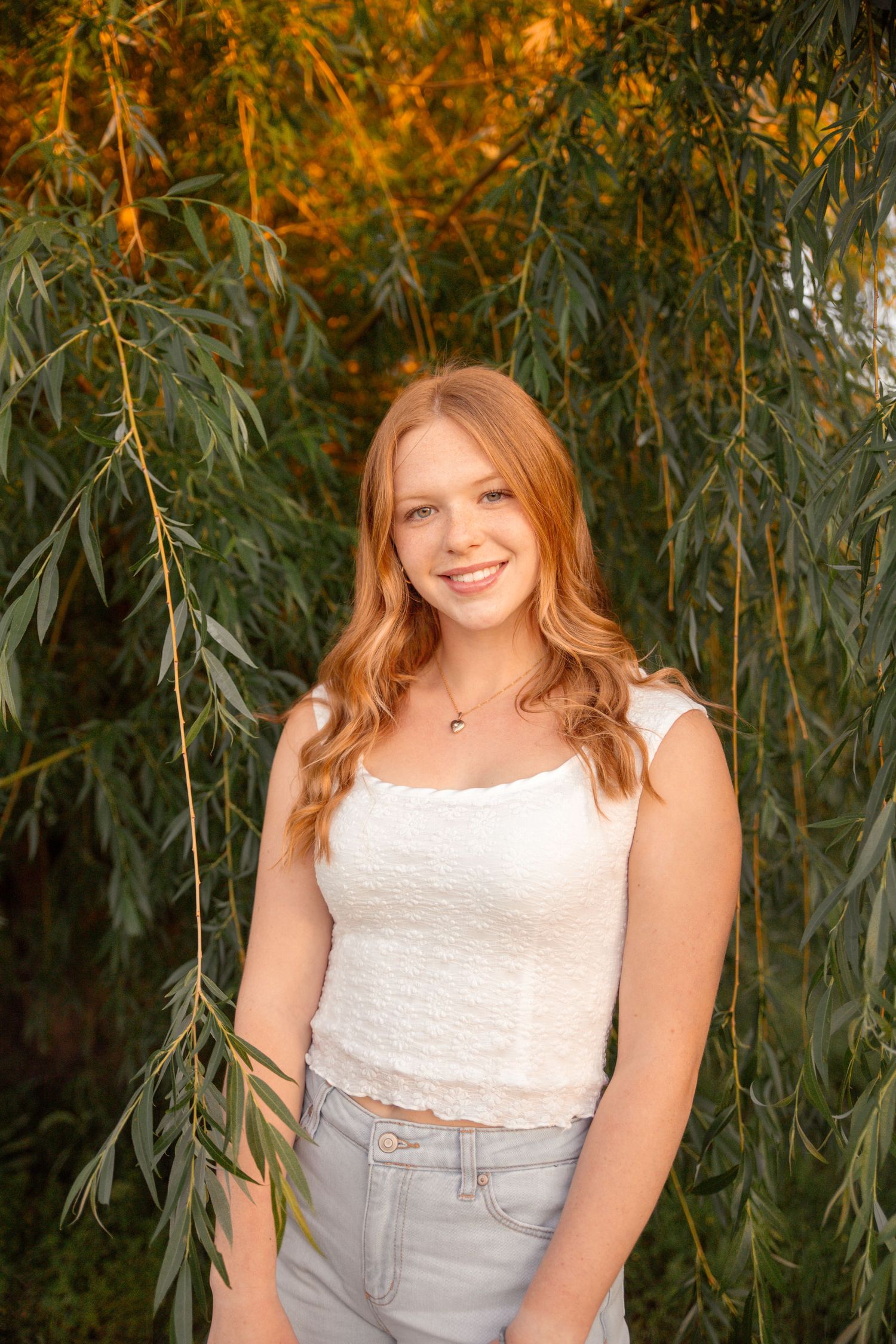 Summer portrait under willow trees with white top and light denim.