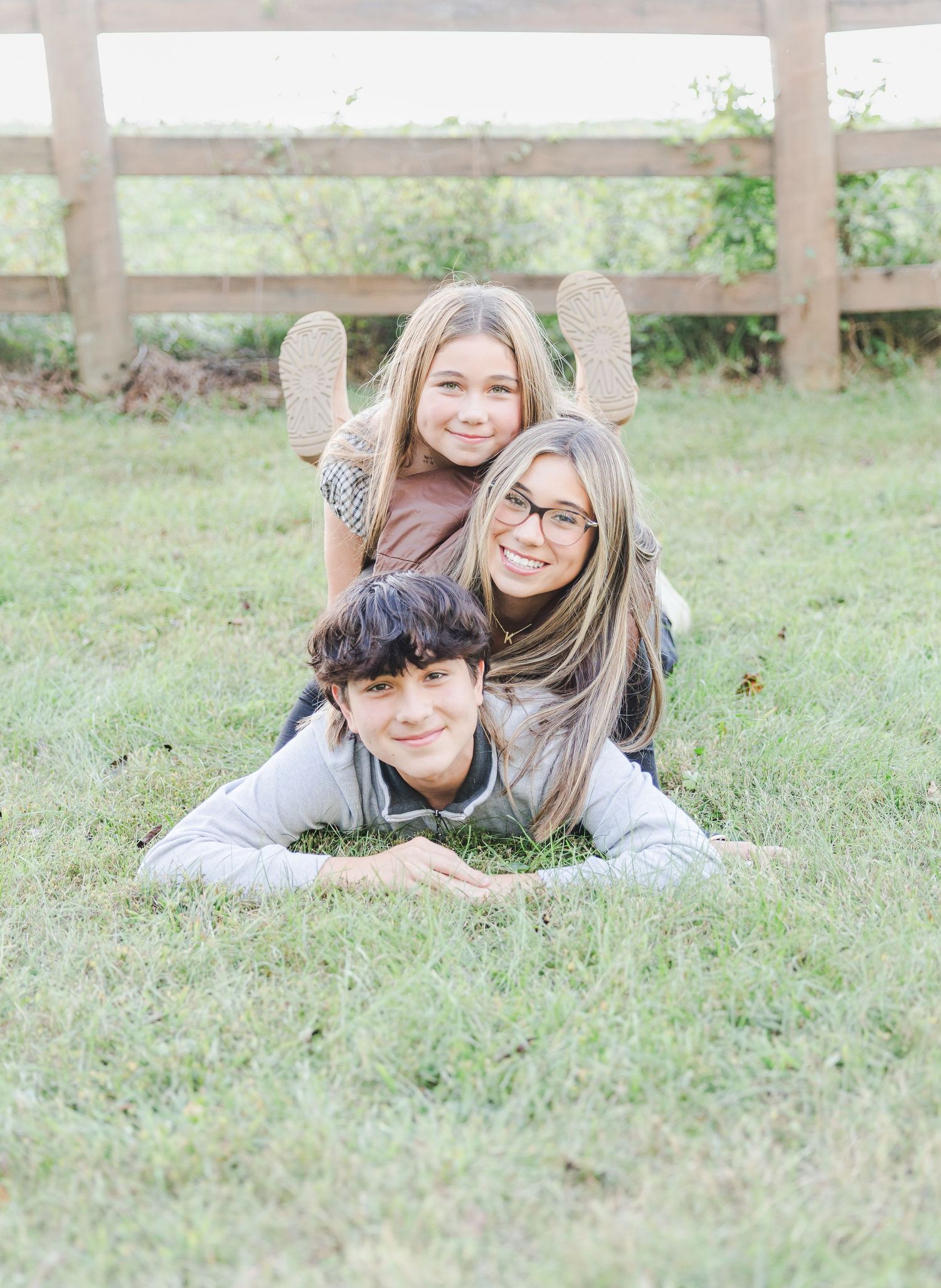 Two people laying on grass and smiling while posing for a casual outdoor photo shoot.