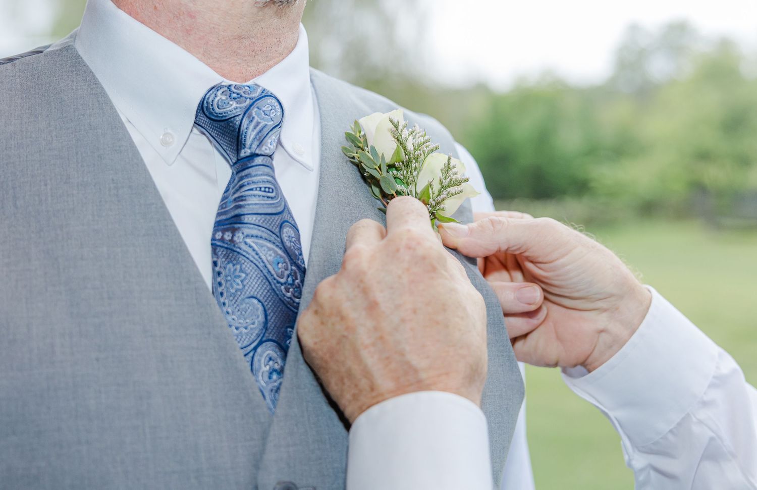 Detail shots of groom's tie and boutonniere being adjusted.