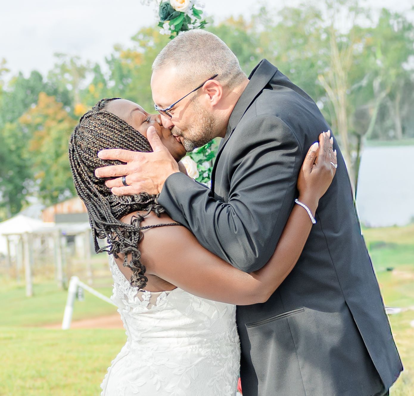 Intimate wedding ceremony kiss captured in close-up under a floral arch.