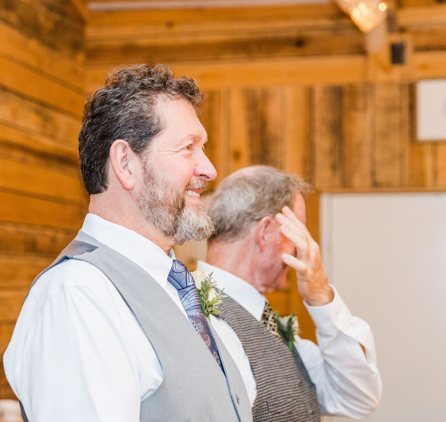 Wedding party members sharing laughs in a rustic wooden barn setting.