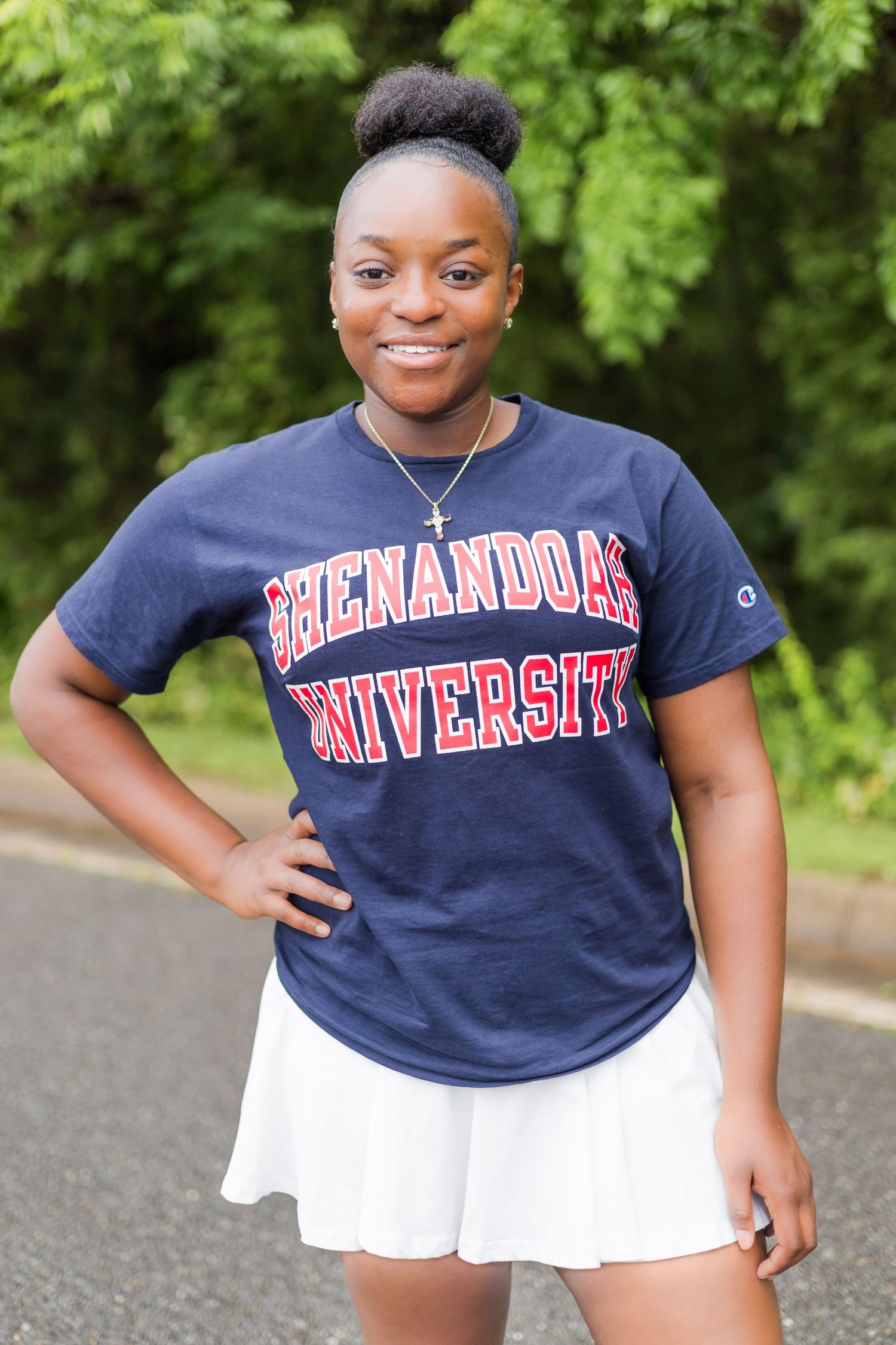 Student in Shenandoah University t-shirt and white skirt poses outdoors.