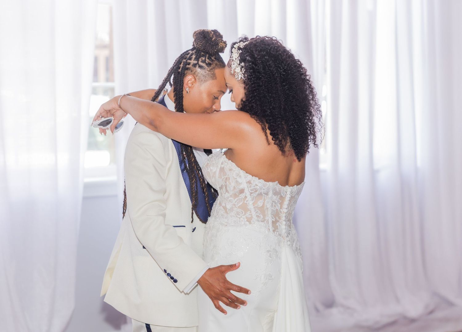 A couple shares an intimate dance moment surrounded by atmospheric fog and white drapes.