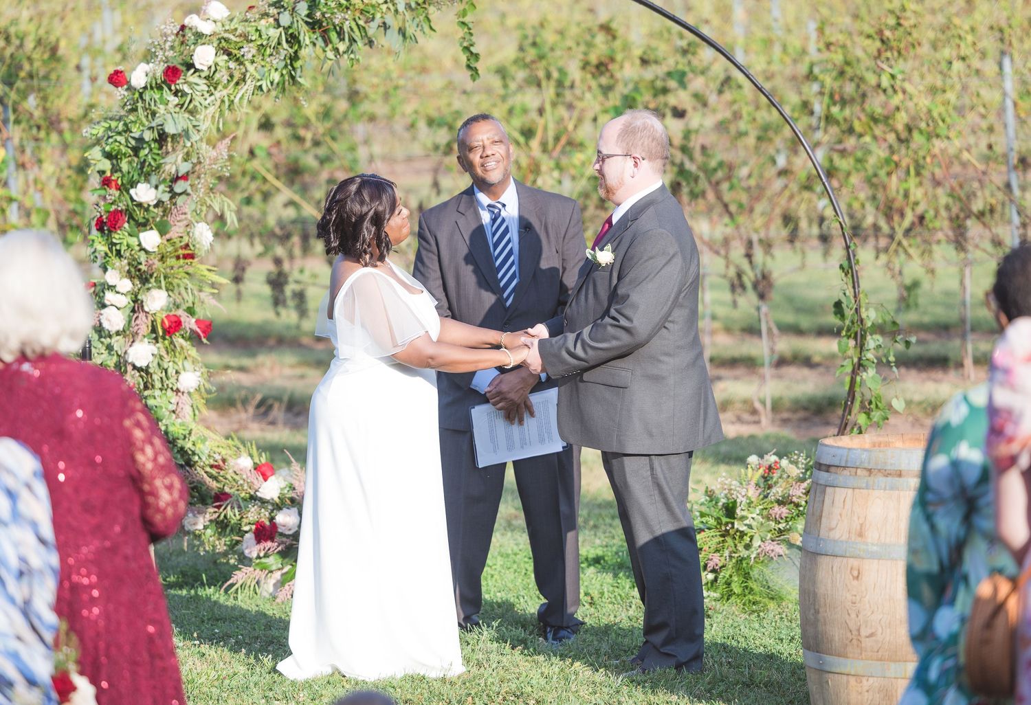 An outdoor wedding ceremony setup with wooden barrels and floral decorations.