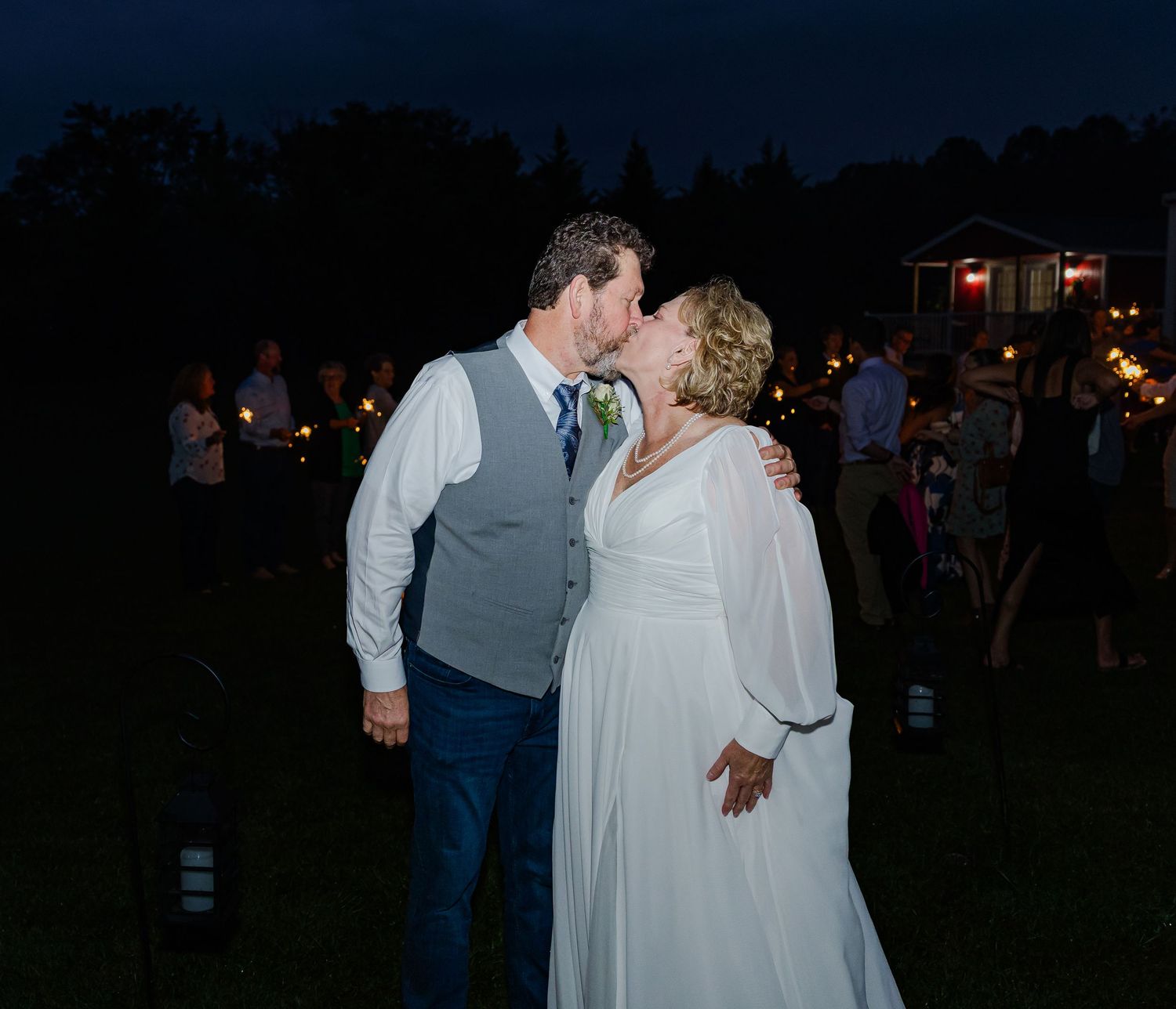 Evening outdoor wedding reception with couples dancing under dark sky.