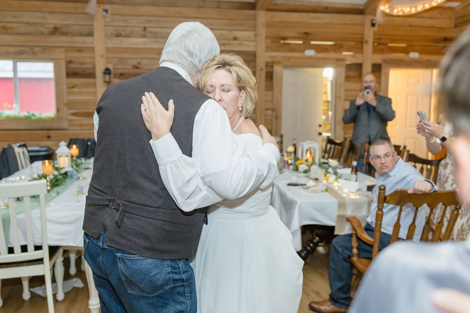 Wedding reception dance floor in rustic wooden barn venue with guests celebrating.