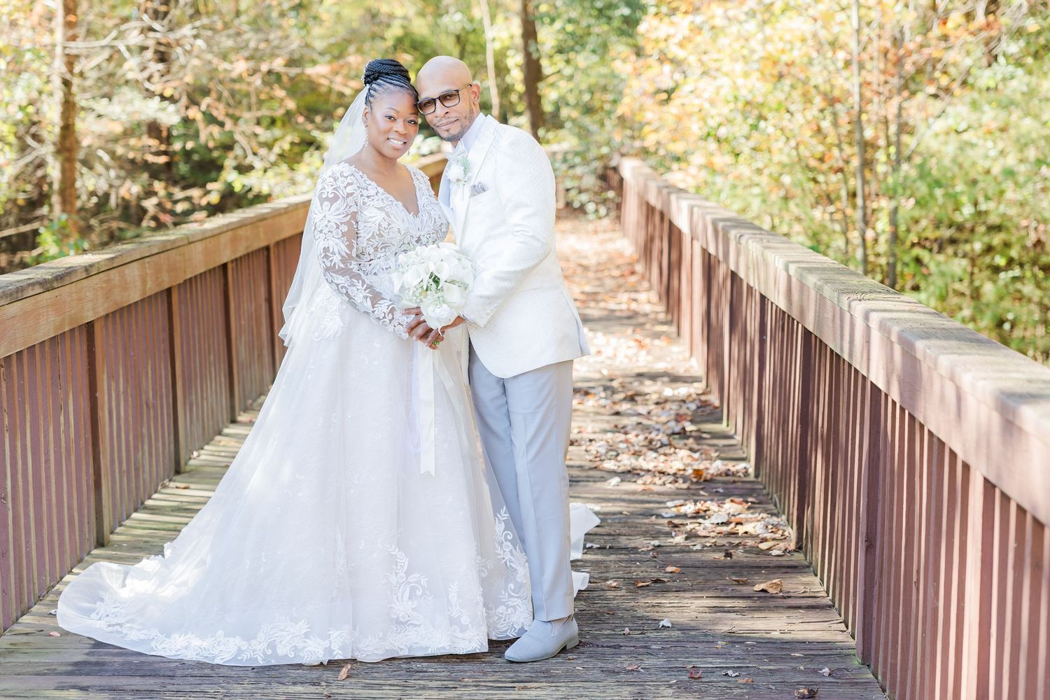Romantic wedding couple shares tender moments on a rustic wooden bridge surrounded by autumn foliage.