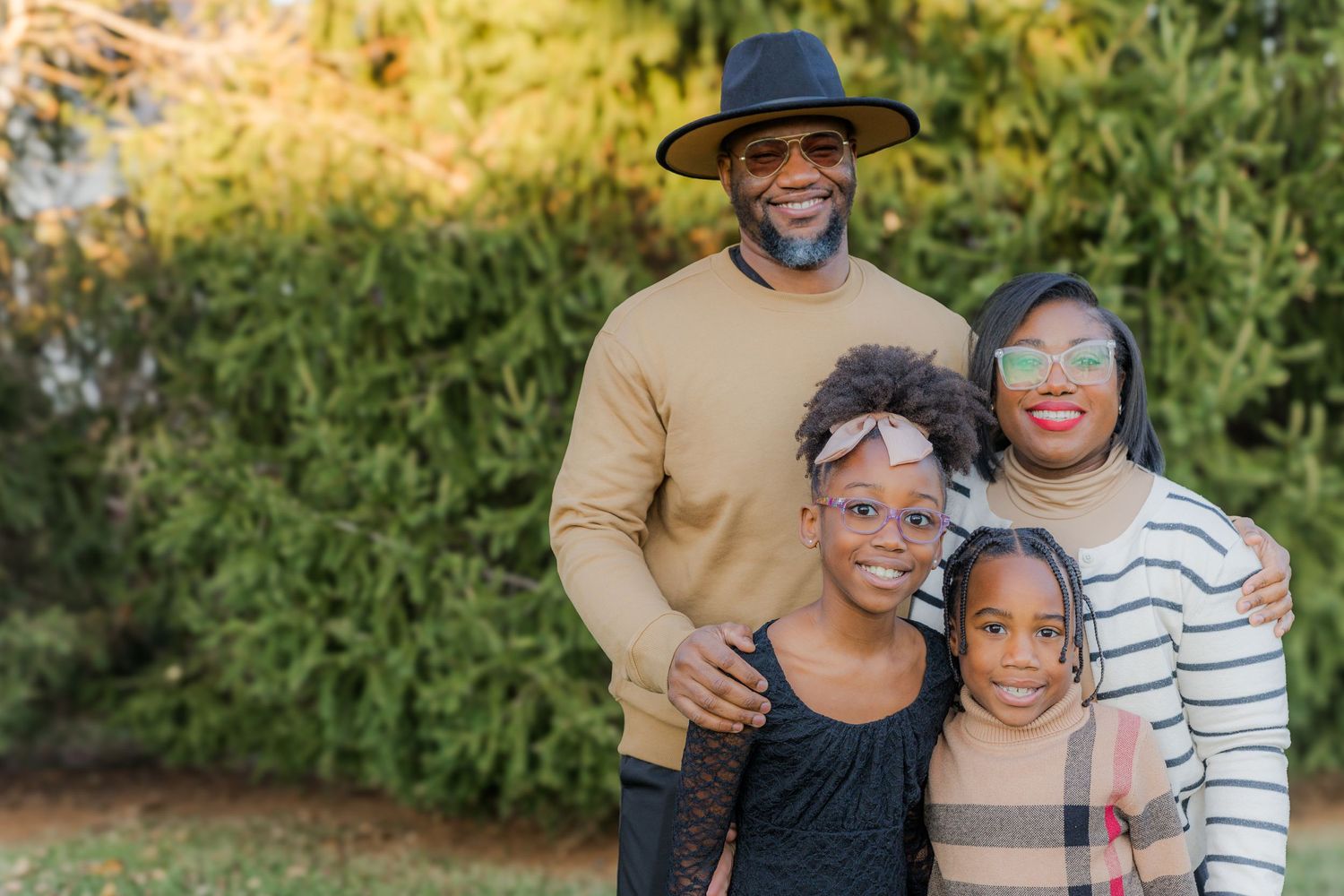 A group poses together outdoors in coordinating neutral-toned outfits for a casual family photo session.