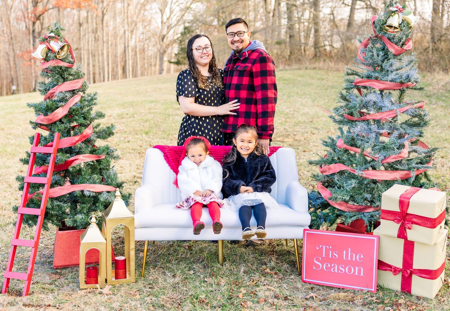 Holiday themed outdoor photo session with decorated Christmas trees and wrapped presents as props.