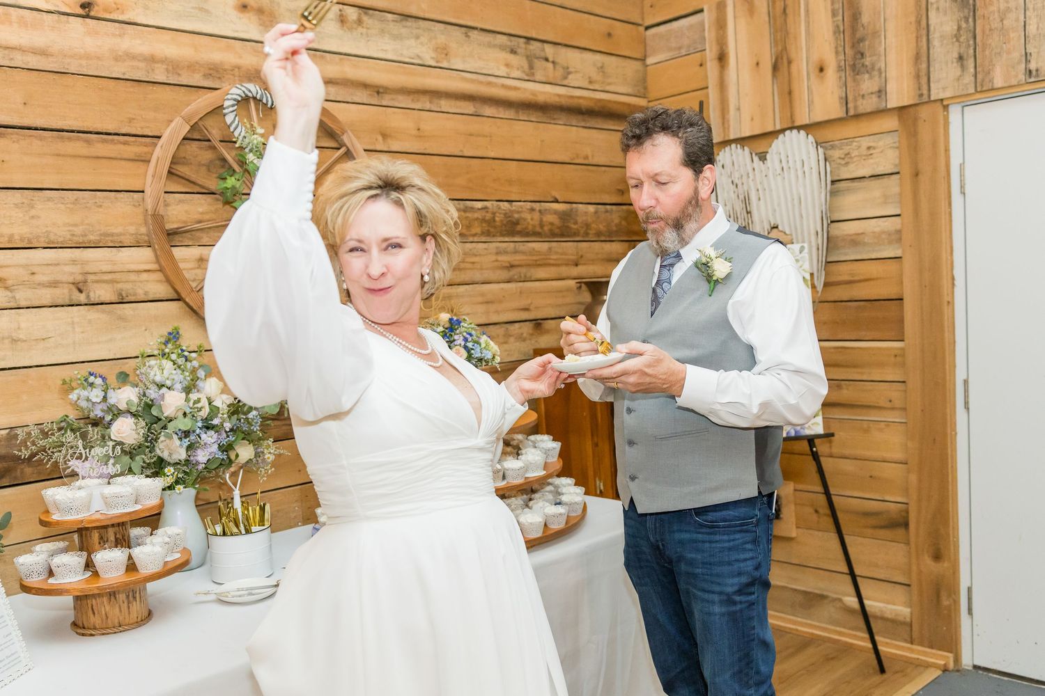 Wedding couple shares first dance in rustic wooden barn venue with warm lighting.