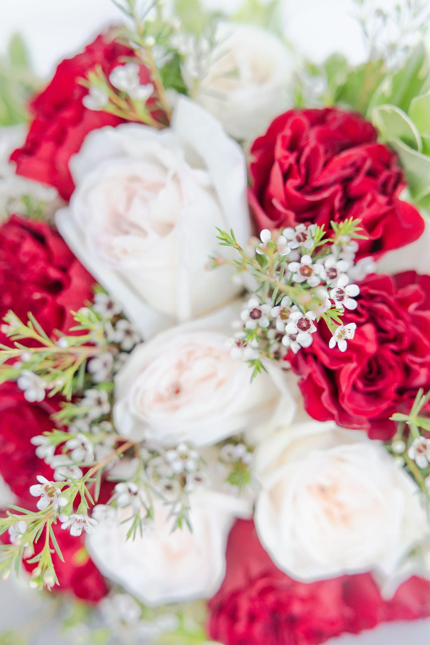 Close-up of romantic wedding bouquet featuring red and white roses with delicate baby's breath.
