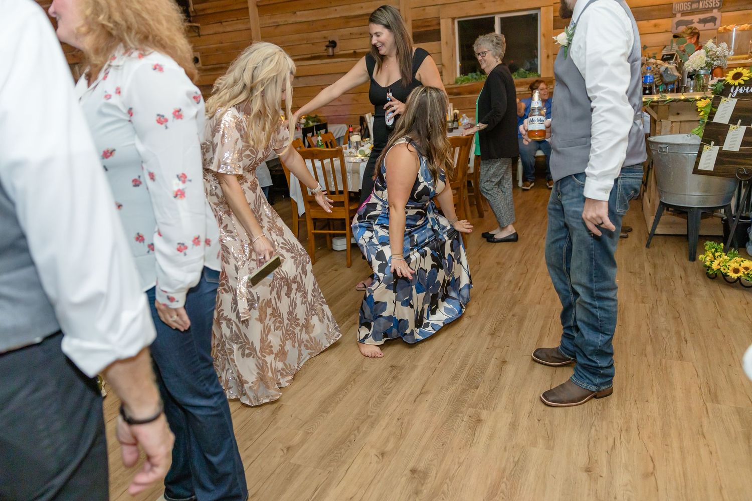 Wedding celebration in wood-paneled venue with guests dancing and mingling.