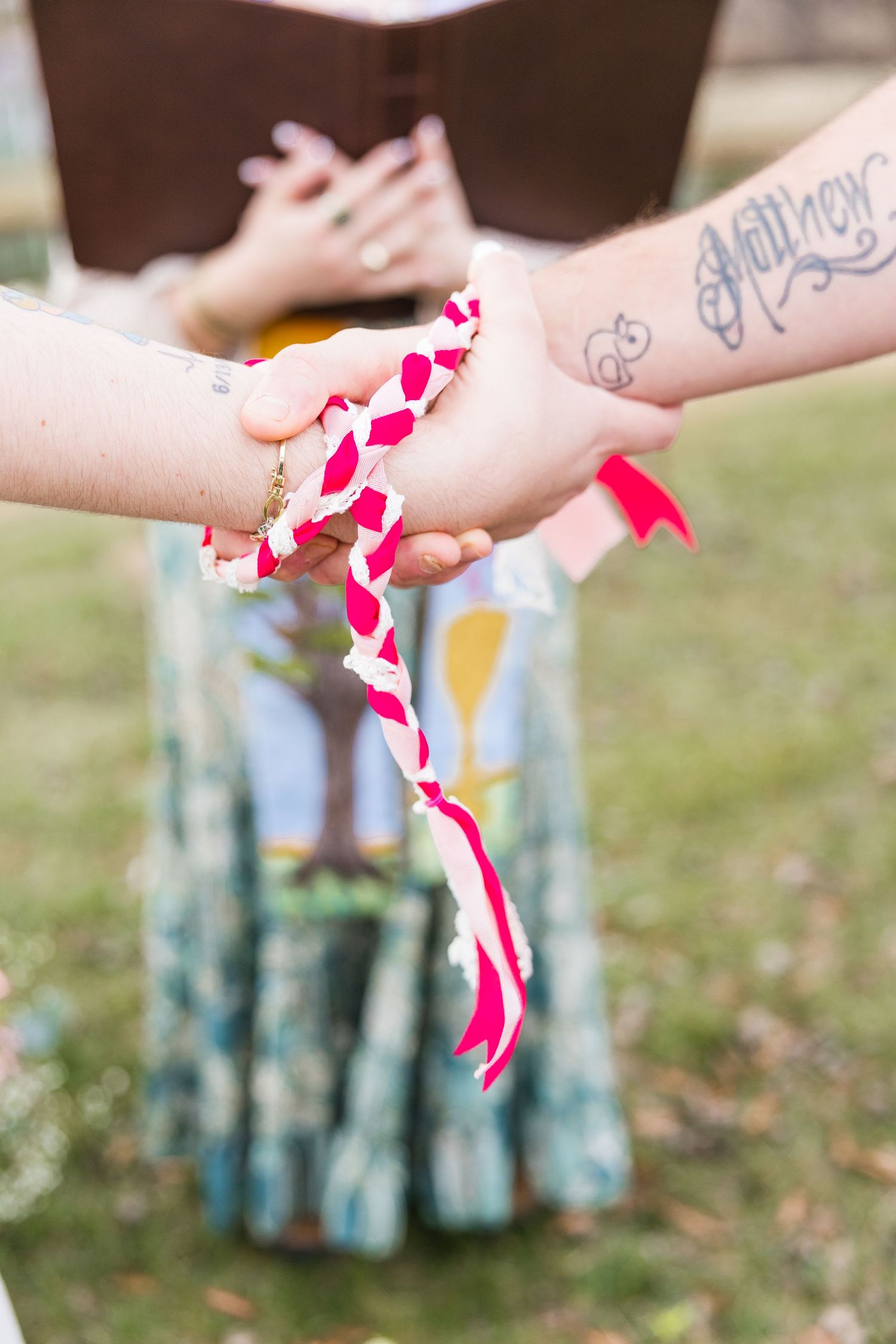 Hands holding a pink and white striped paper straw with blue mason jars in the background.